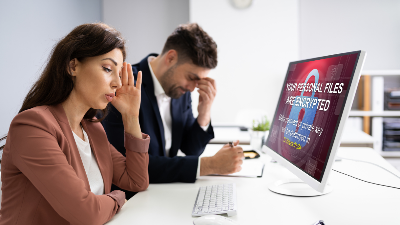 Distressed woman and man infront of computer that has an error messaging stating their data has been encrypted and they have a time limit to pay a ransom to get it back