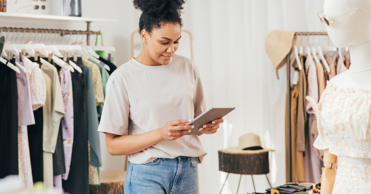 female store owner in clothing store looking down at an ipad